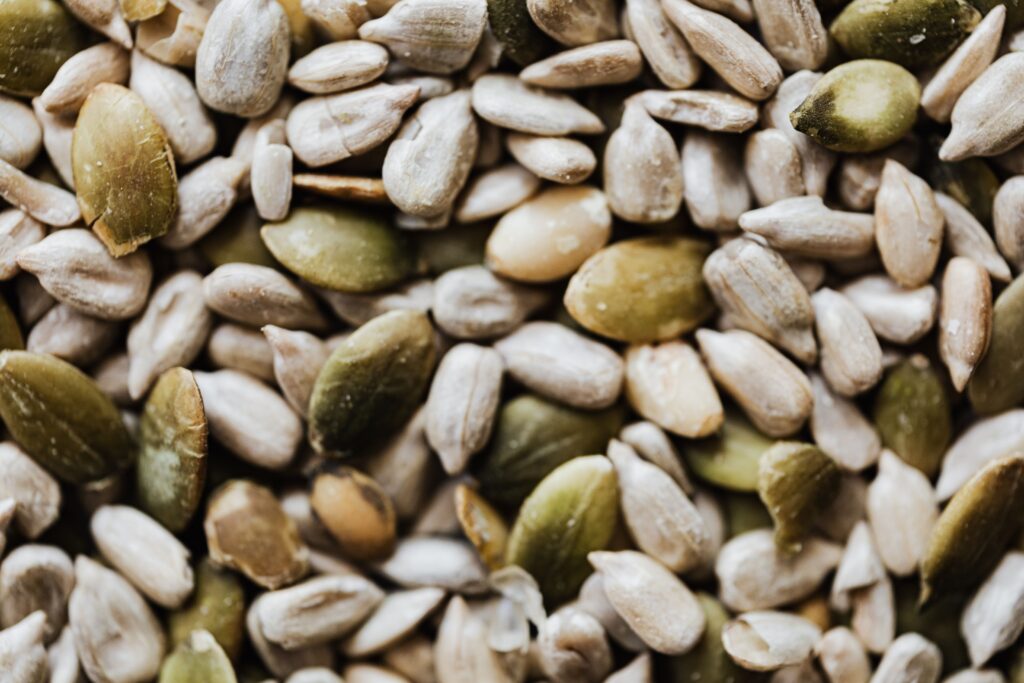 Closeup top view of heap of green and grey pumpkin seeds with cracks on rough shell